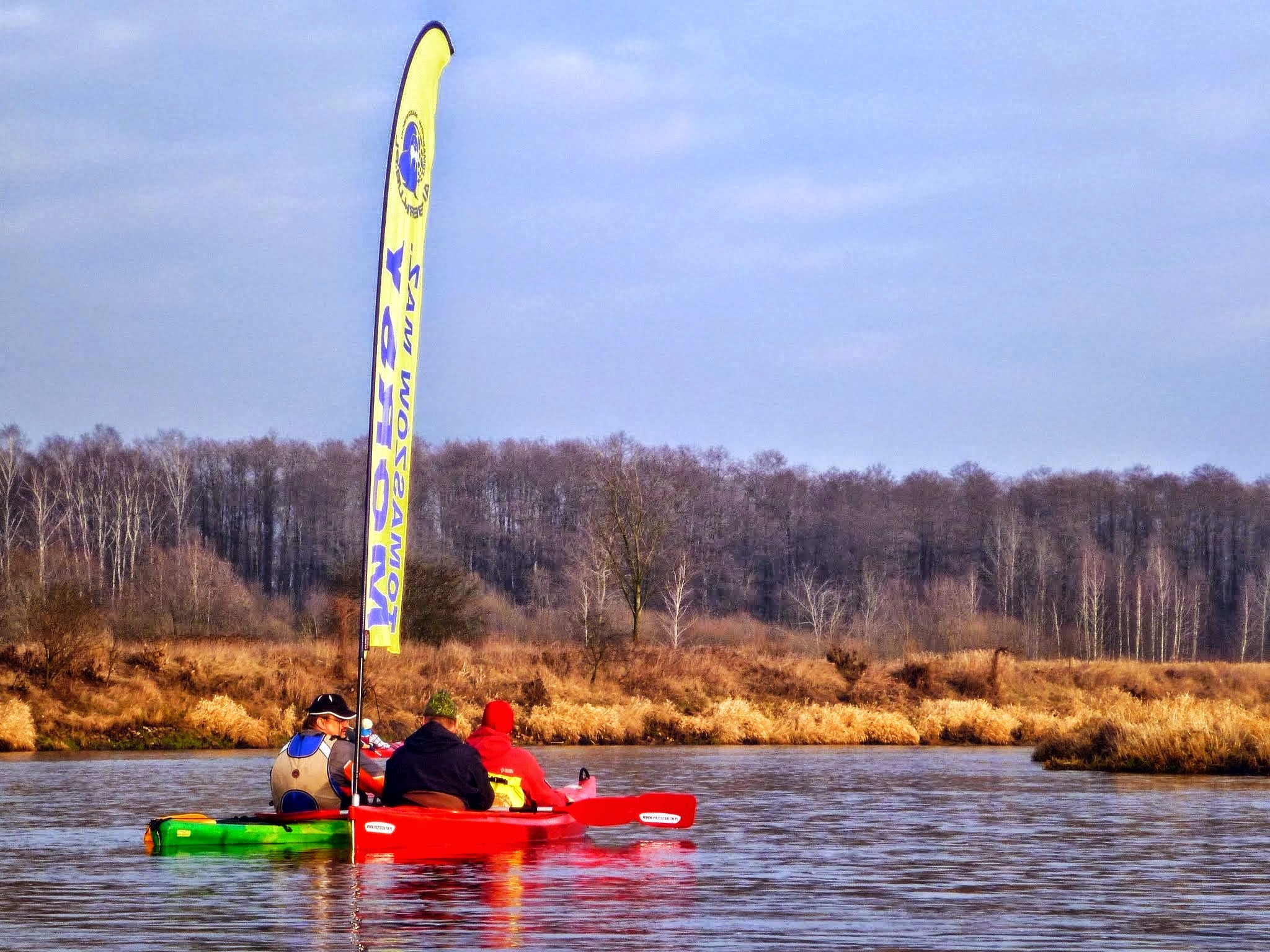 Kolorowe kajaki na zimowej Pilicy z flagą klubową